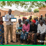 Community feedback mechanism participation in action: local NGO staff demonstrating Grievance App on tablet and smartphone to rural villagers under a tree