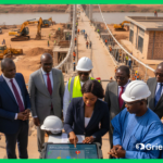 African government and project officials reviewing early warning GRM data during a large infrastructure project, illustrating development project risk mitigation.